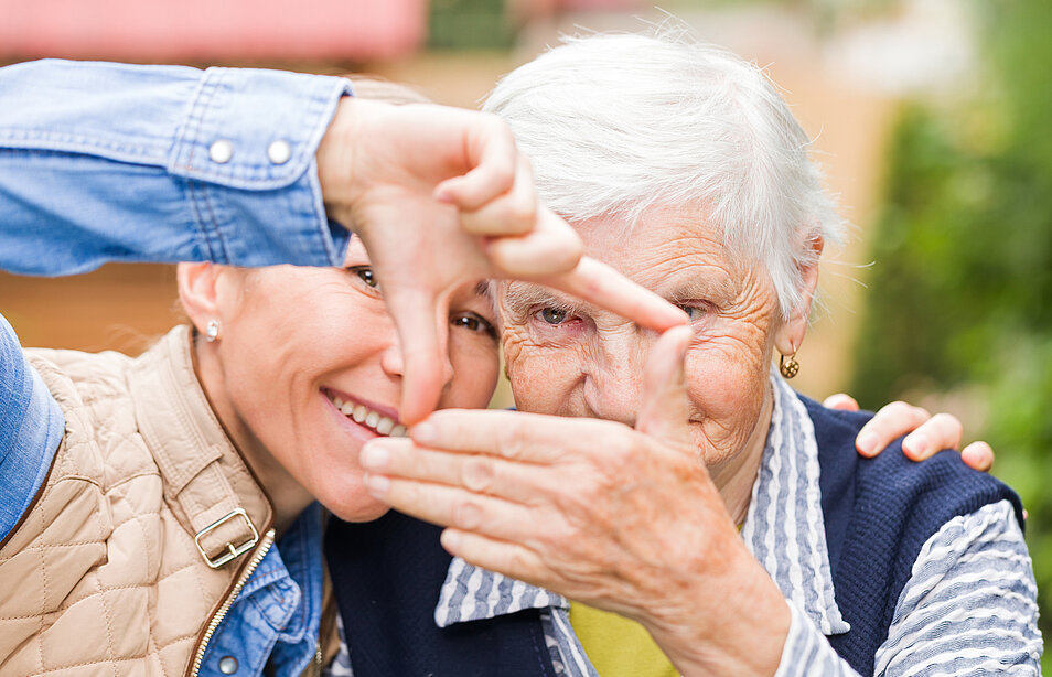 Frau und Senioren formen zusammen mit ihren Händen ein Symbol